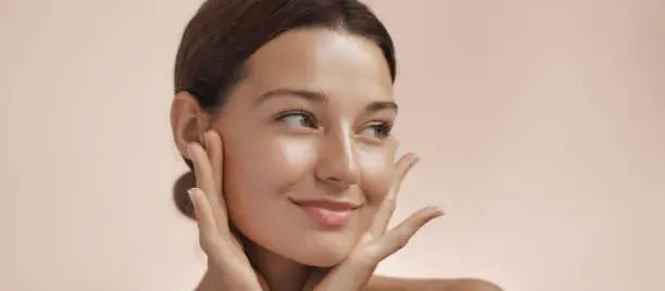 Close-up of a woman applying niacinamide serum to her glowing skin, showcasing its benefits for skincare.
