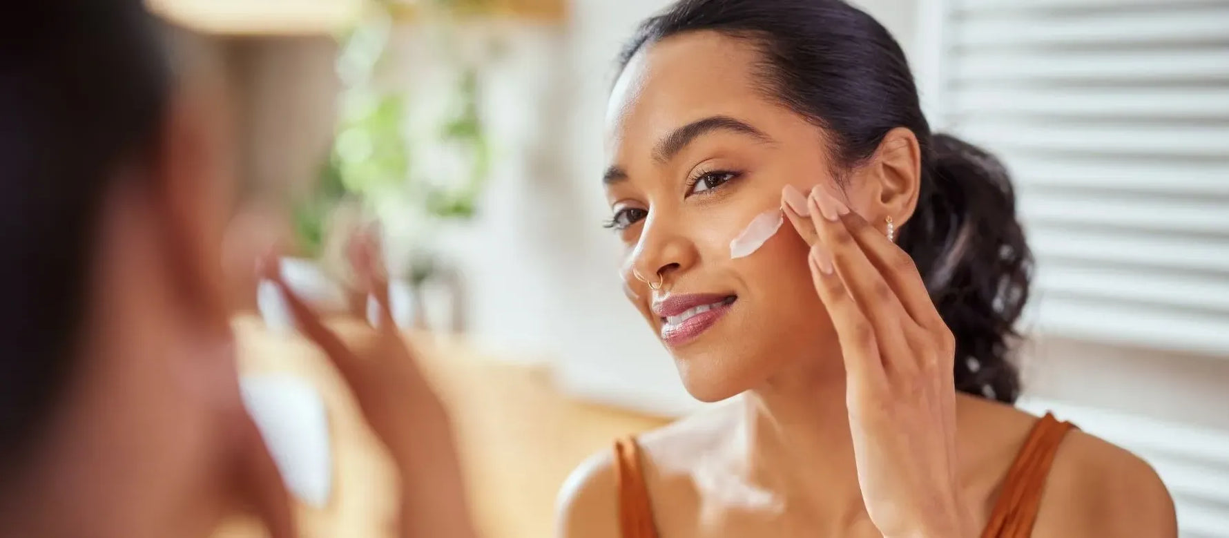 A woman applying vitamin C face wash in a bright bathroom, exploring skincare benefits for glowing skin.