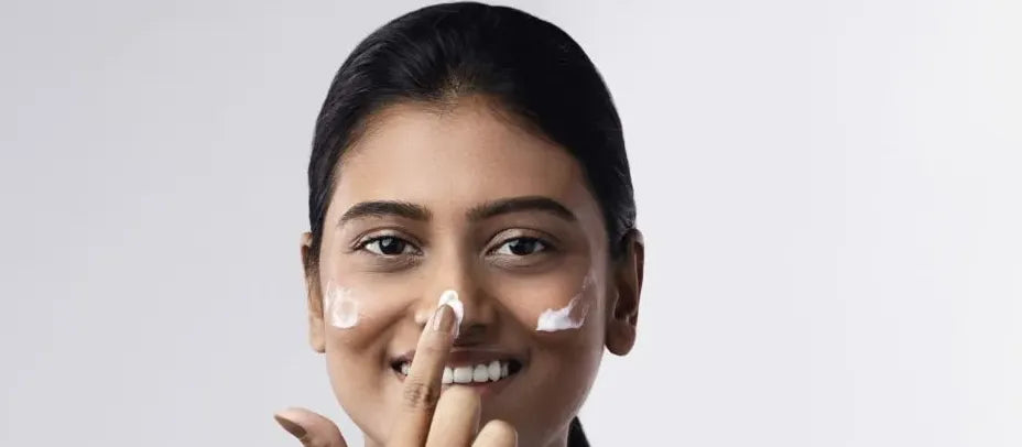 A woman applying moisturizer to her face, showcasing effective skin hydration techniques for healthy skin.