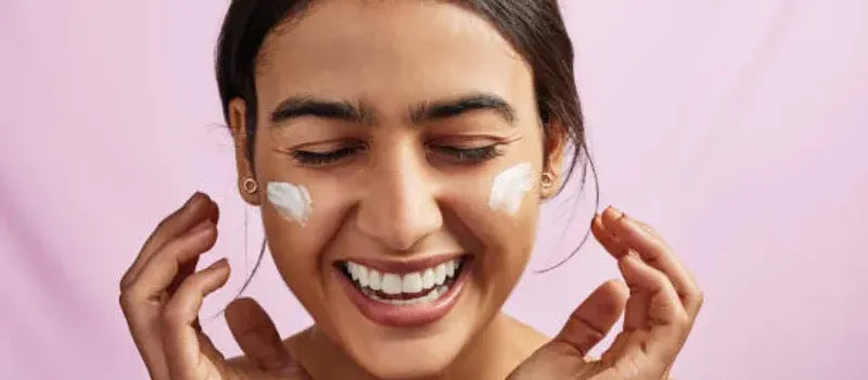 A woman applying an oil-free moisturizer, showcasing her radiant skin and healthy glow.