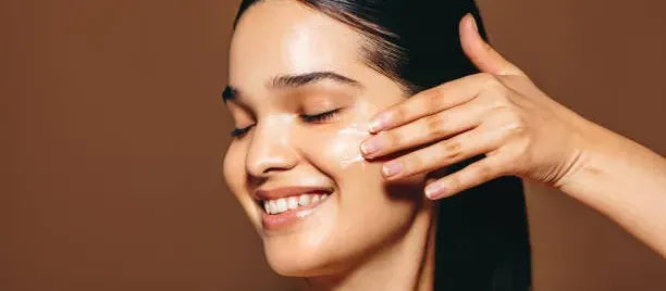 A woman applying niacinamide serum to her face, showcasing its benefits for glowing skin.