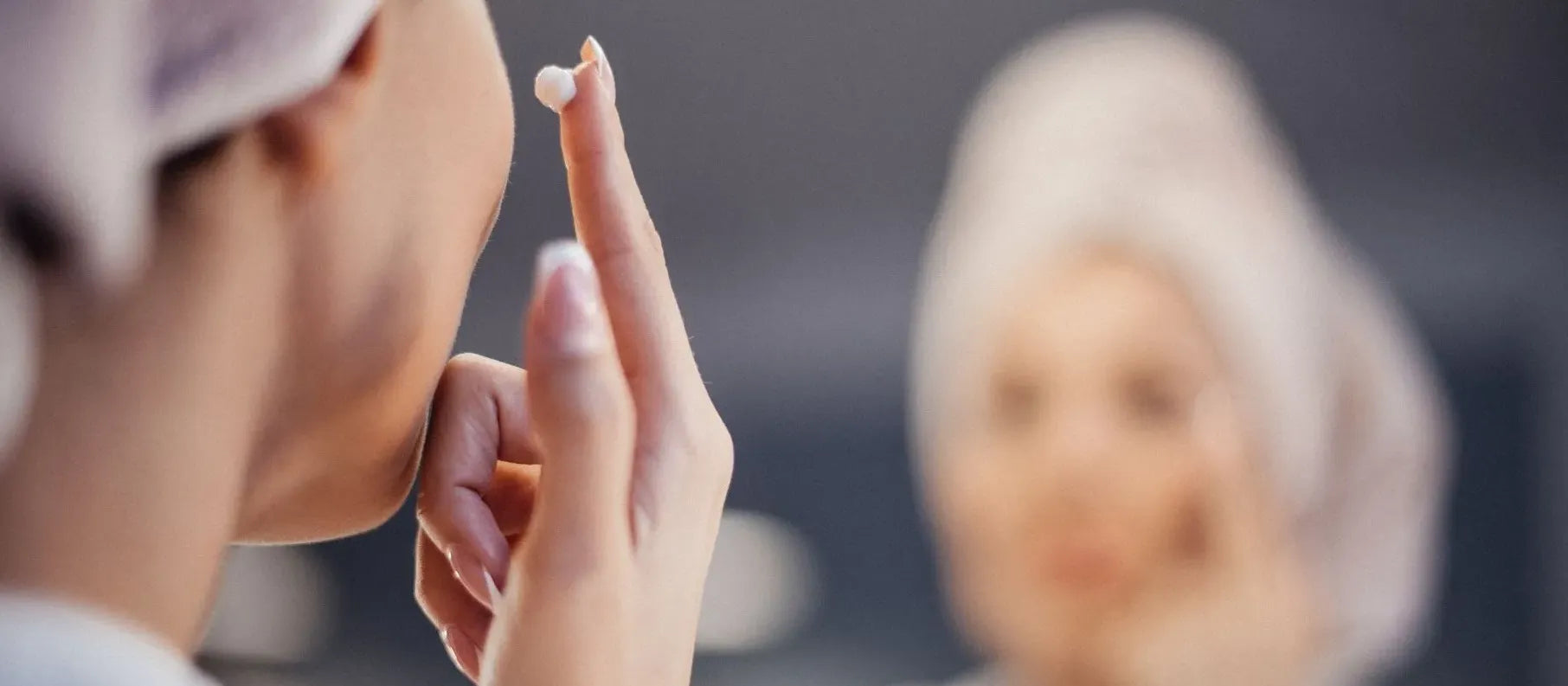 Close-up of a woman applying a clay mask to her face, targeting oily skin and minimizing open pores.