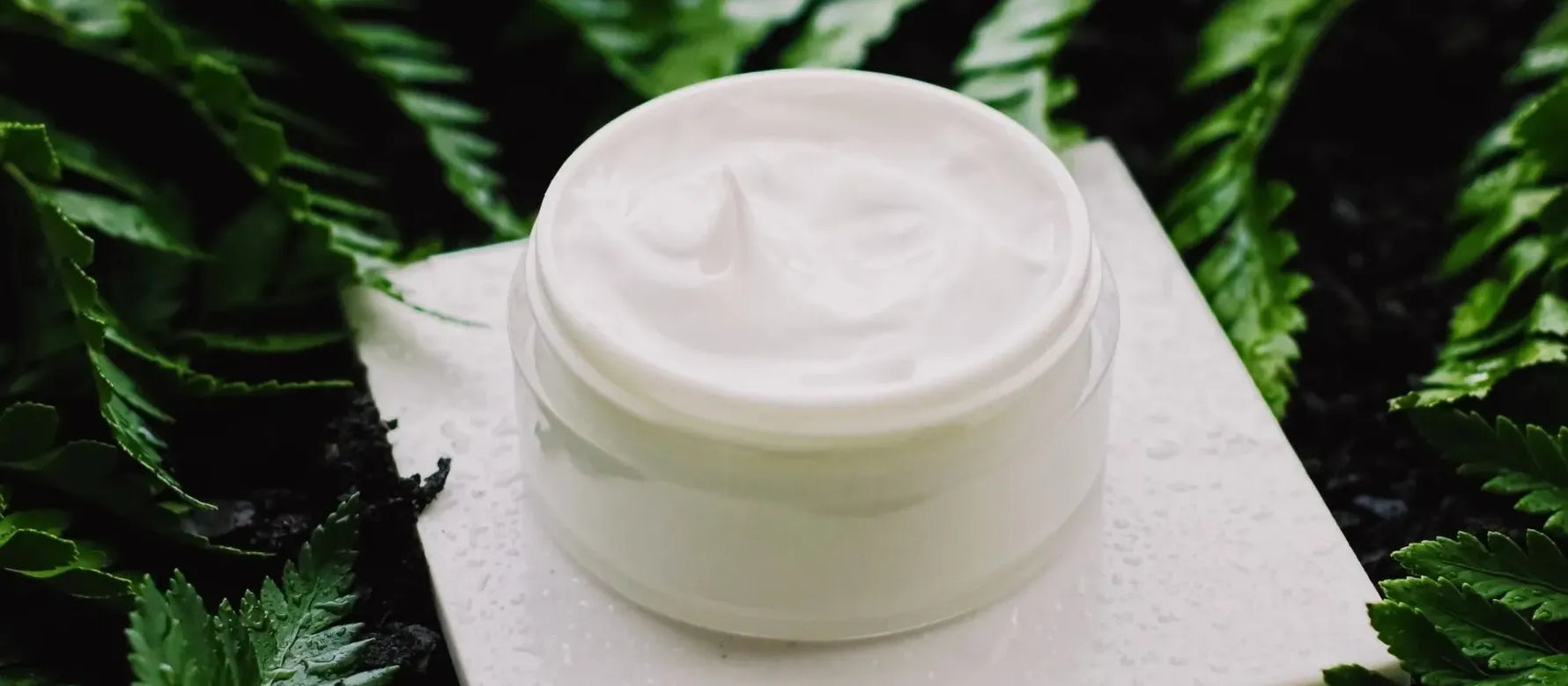 A woman applying a gentle skin cleanser to her face, promoting daily skincare routines for healthy skin.