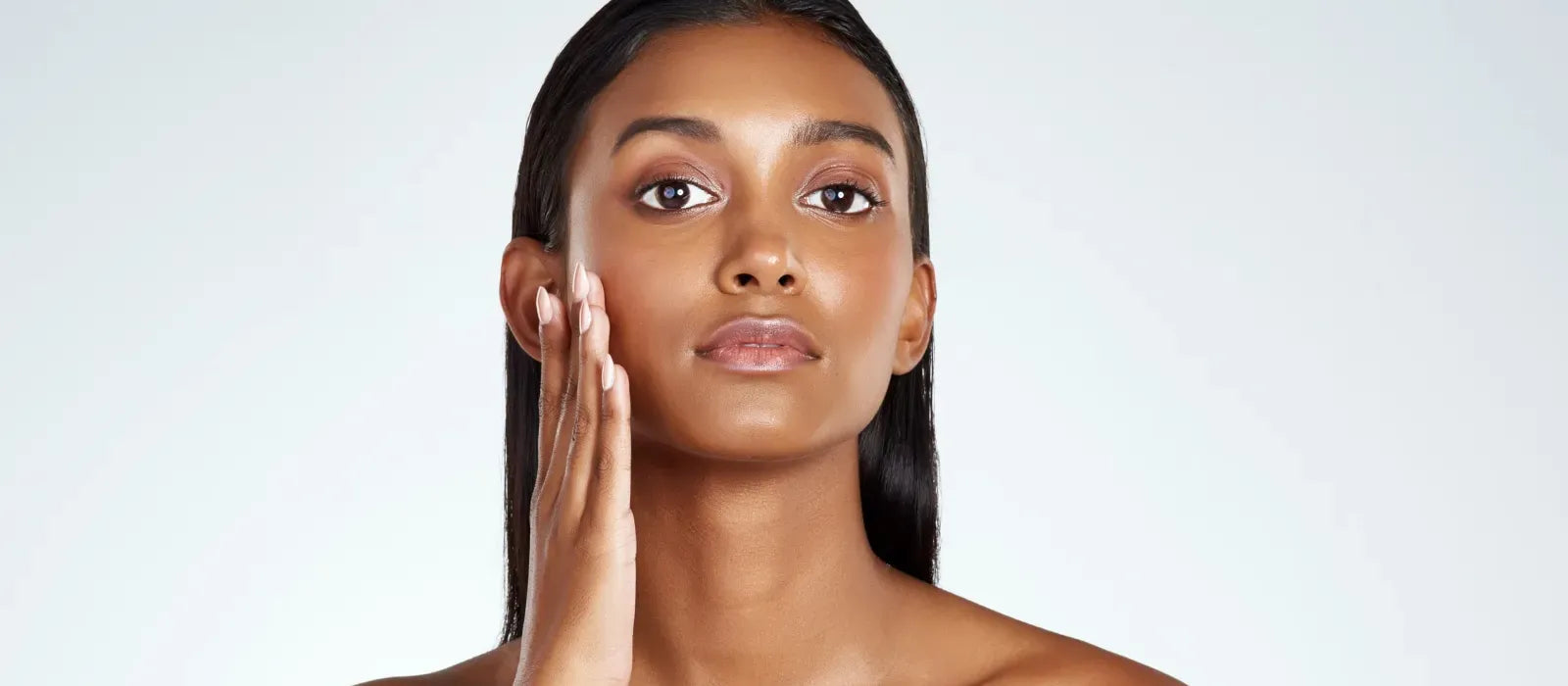 A woman applying moisturizer cream to her glowing skin, showcasing the benefits of effective skincare.