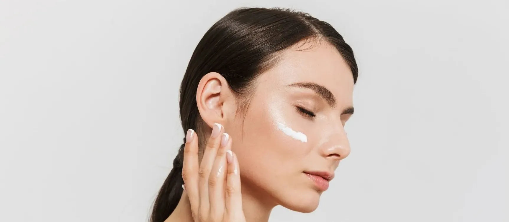 Close-up of a glowing face applying acne cream for radiant skin and clear complexion.