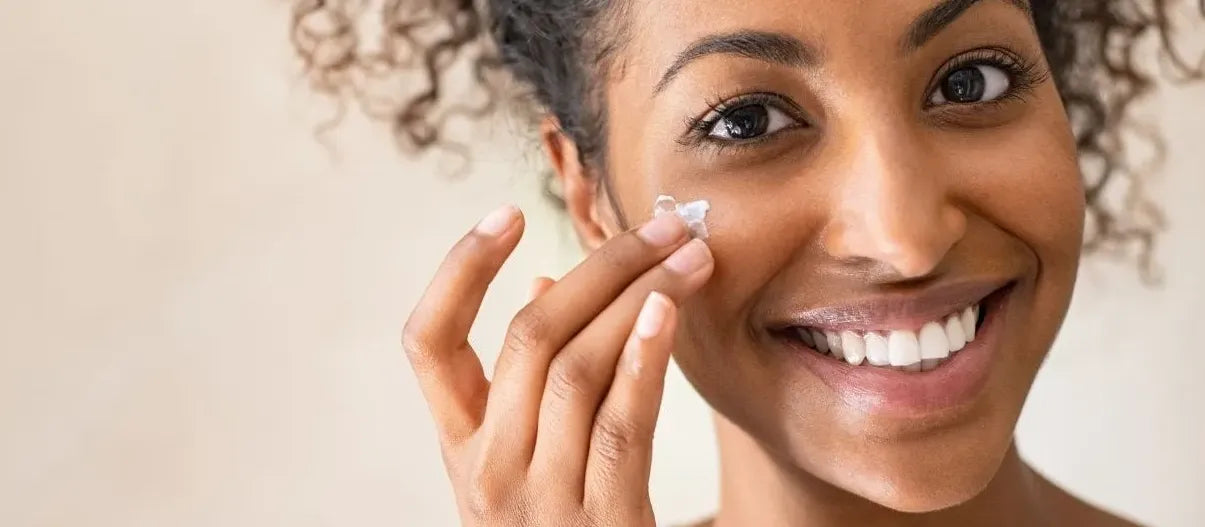 A woman applying a hydrating moisturizer to her face for radiant, glowing skin.